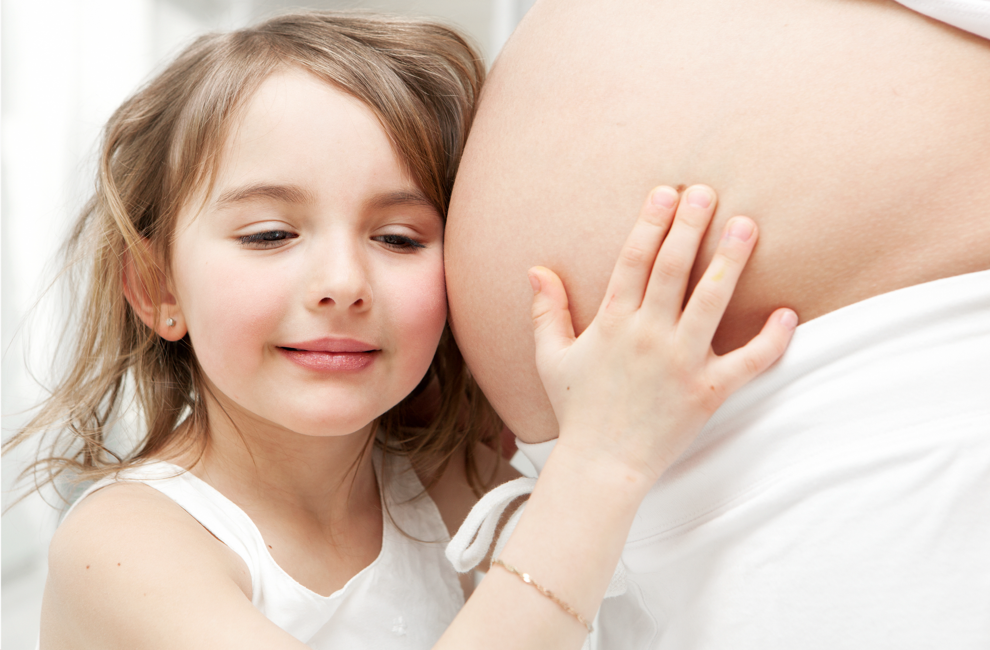 a little girl is hugging her mother's pregant stomach